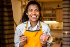 Mulher sorridente segurando um pote de cerâmica, representando pequenos negócios e profissionais autônomos.